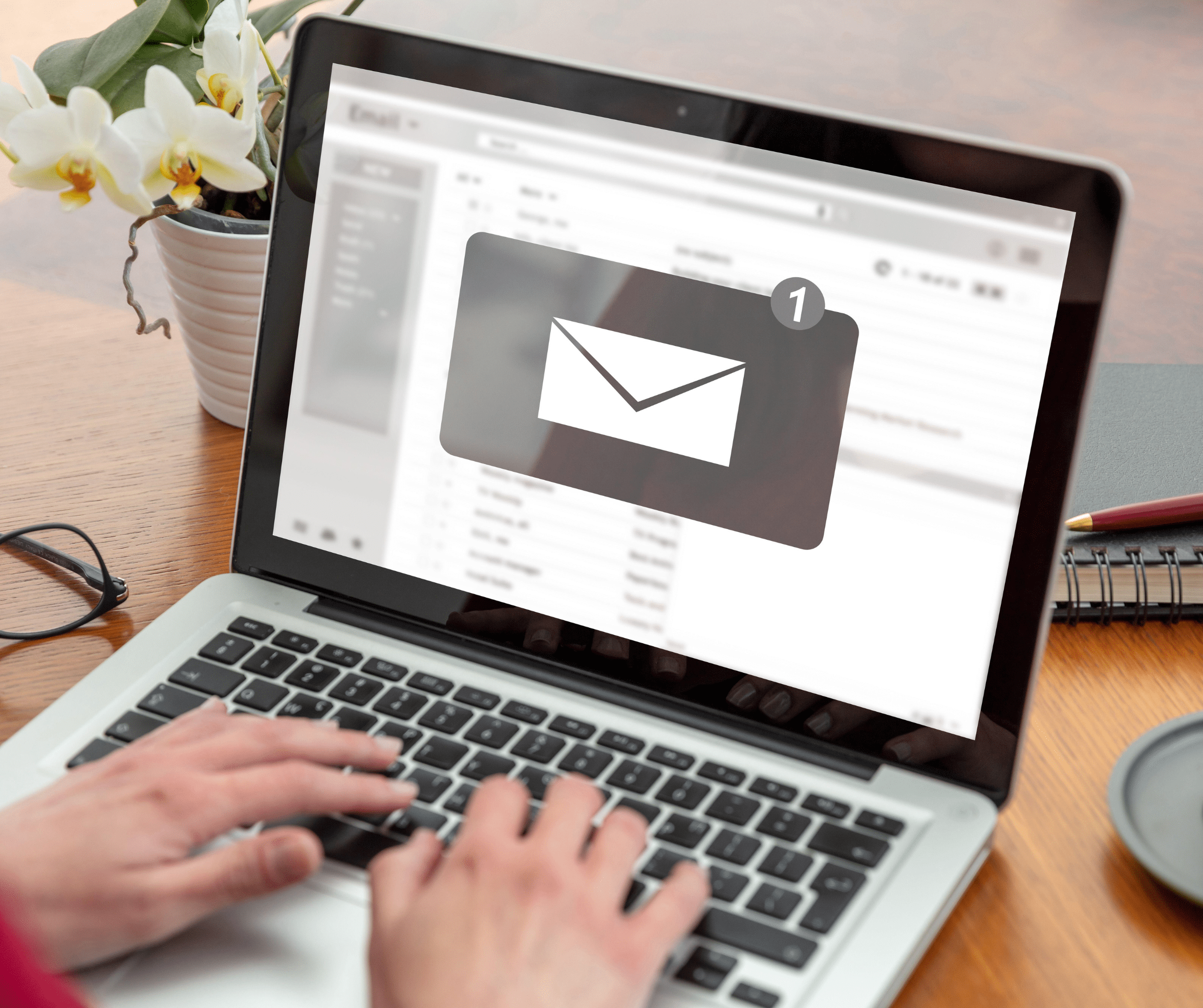 Person typing on a laptop displaying an email inbox with a new message notification