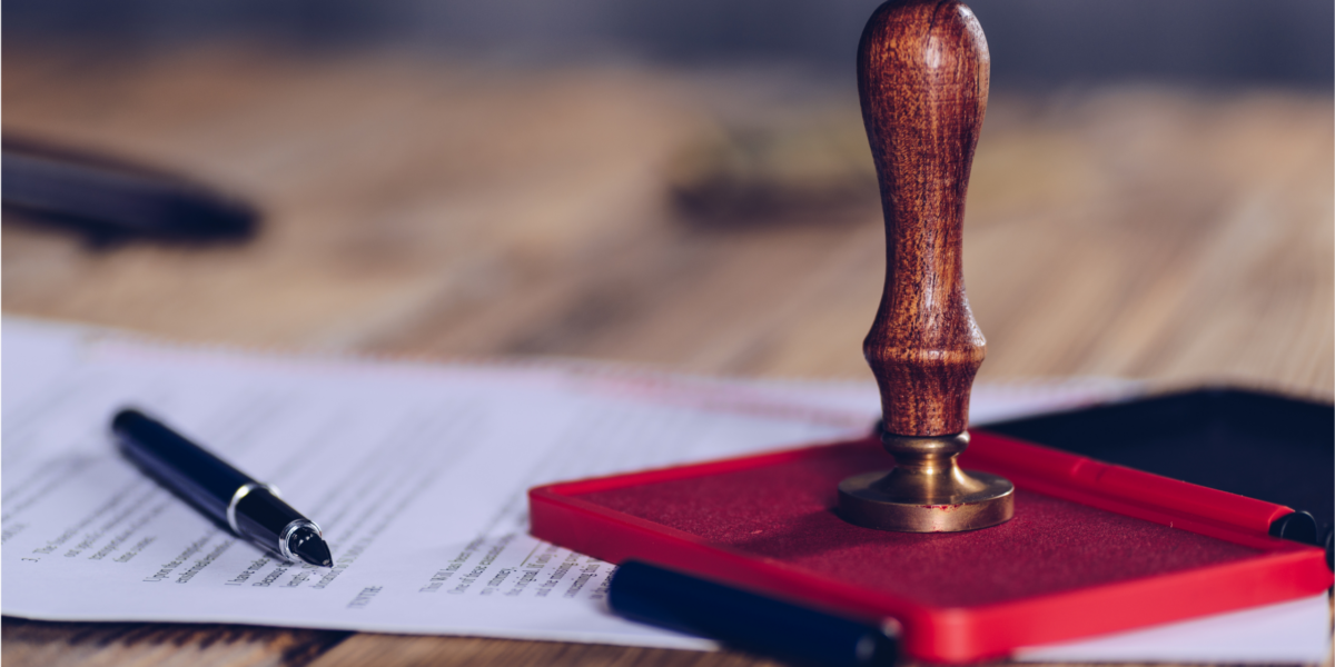3 A wooden rubber stamp resting on a red ink pad beside a pen and a document