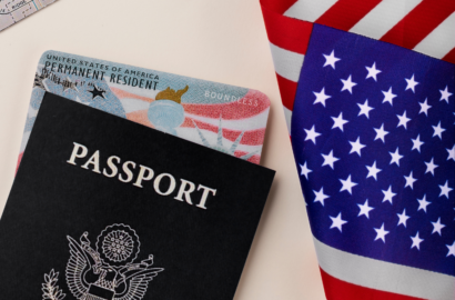 A US passport and Permanent Resident green card resting on the American flag