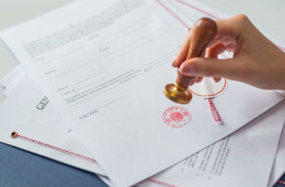 A hand stamping an official seal onto a notarized legal document